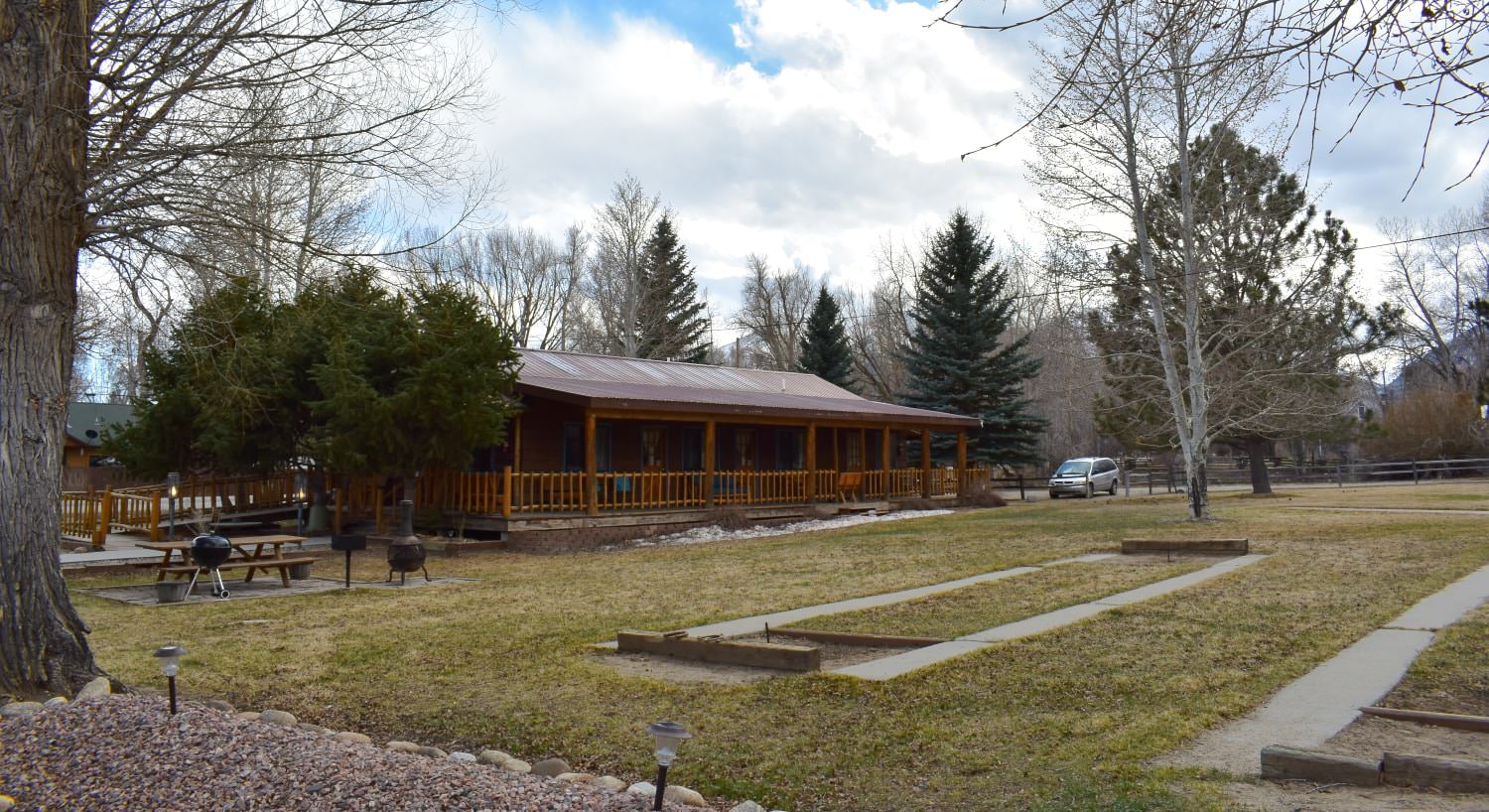 Large wooden lodge surrounded by green grass and large trees