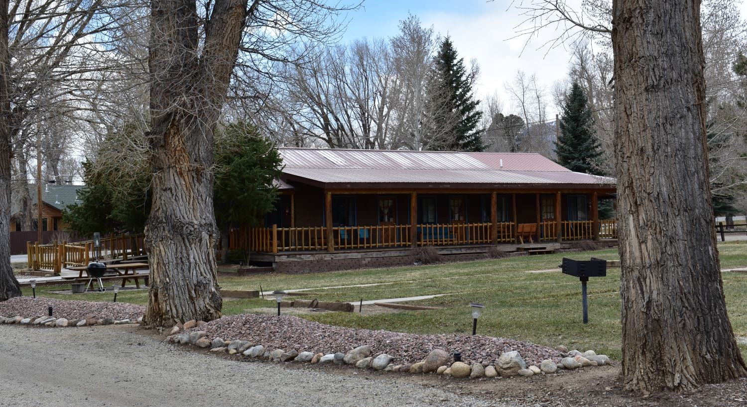 Large wooden lodge surrounded by green grass and large trees